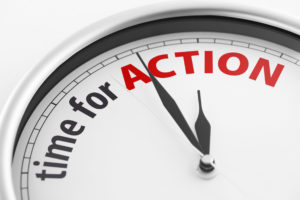 Close-up of a clock showing the words "Time For Action". Shallow depth of field.