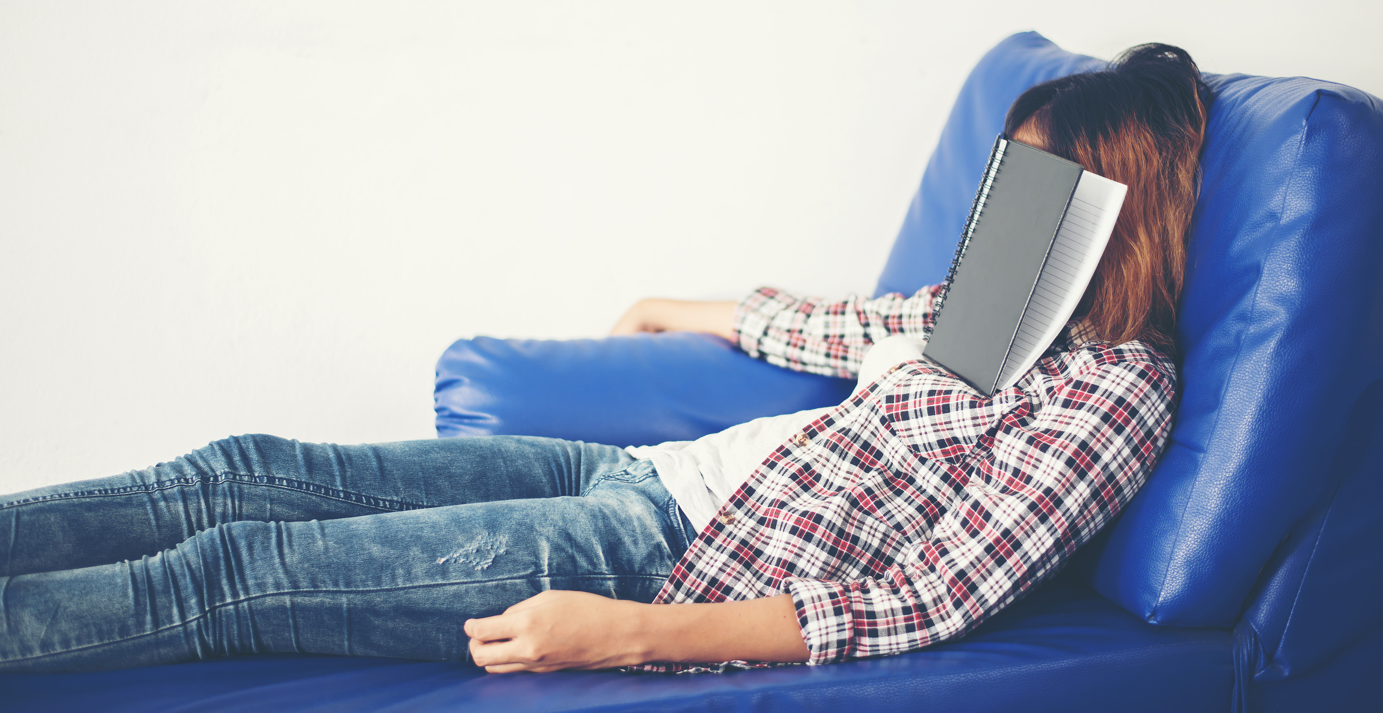 Young beautiful woman sleeping on blue sofa tired for writing.