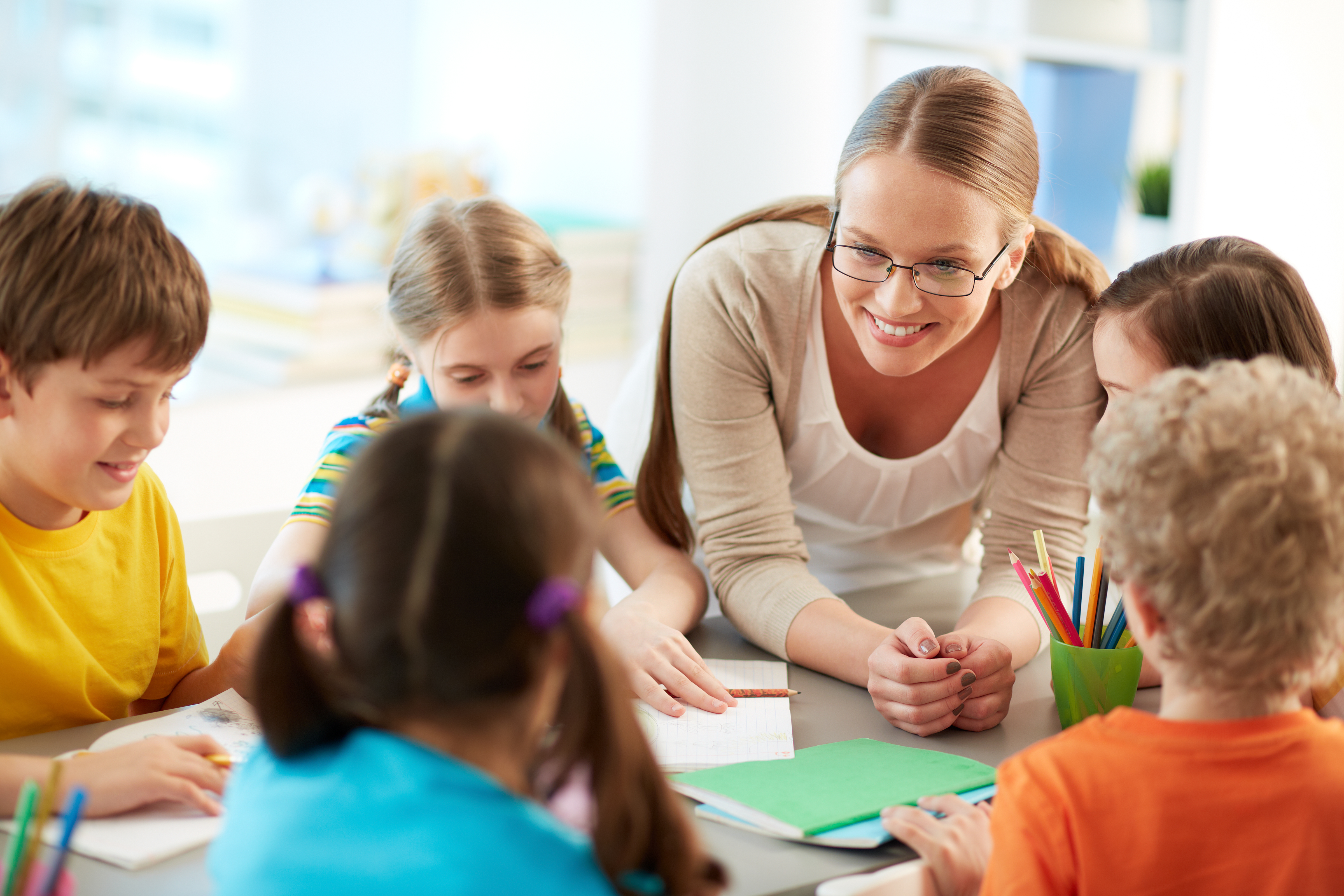 Portrait of diligent schoolkids and their teacher talking at lesson